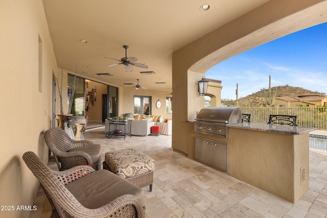 view of patio / terrace featuring fence, exterior kitchen, ceiling fan, and a grill