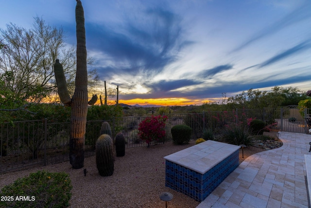 yard at dusk featuring fence and a patio