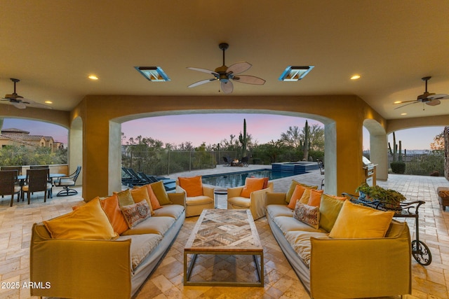 patio terrace at dusk featuring fence, outdoor dining area, ceiling fan, and an outdoor living space