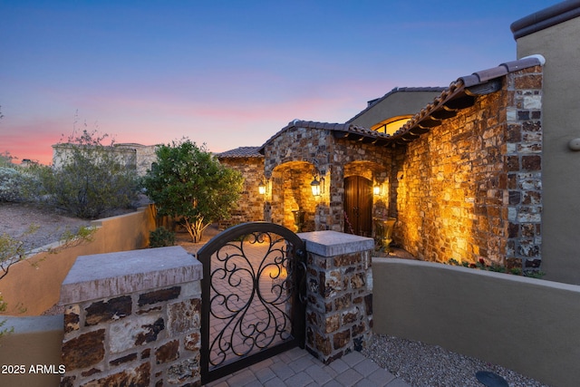view of front of property with a tiled roof, a fenced front yard, a gate, and stucco siding