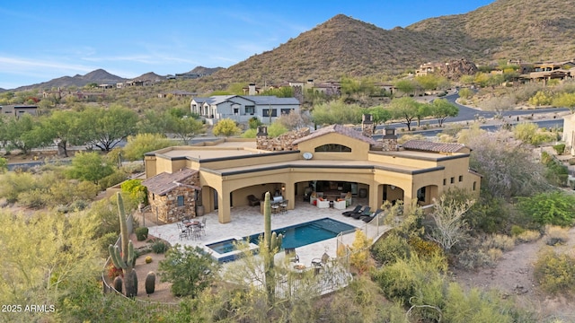 exterior space with a patio, a pool with connected hot tub, a mountain view, and stucco siding