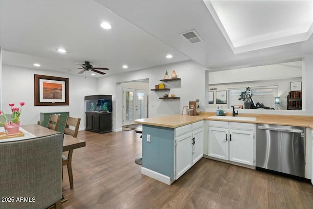 kitchen with dark wood-style floors, visible vents, a peninsula, a sink, and stainless steel dishwasher