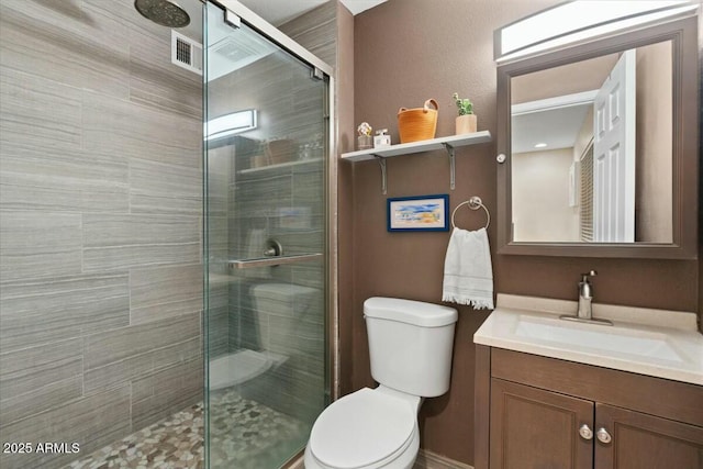 full bathroom featuring toilet, a stall shower, and vanity