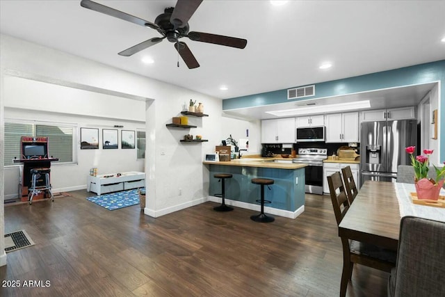 kitchen with stainless steel appliances, dark wood-type flooring, visible vents, and a peninsula