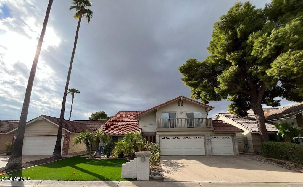 view of front property with a front yard, a balcony, and a garage