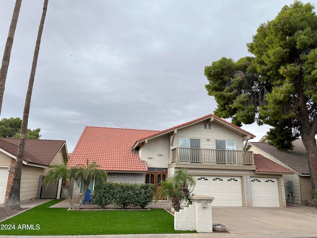 view of front of property with a balcony, a front yard, and a garage