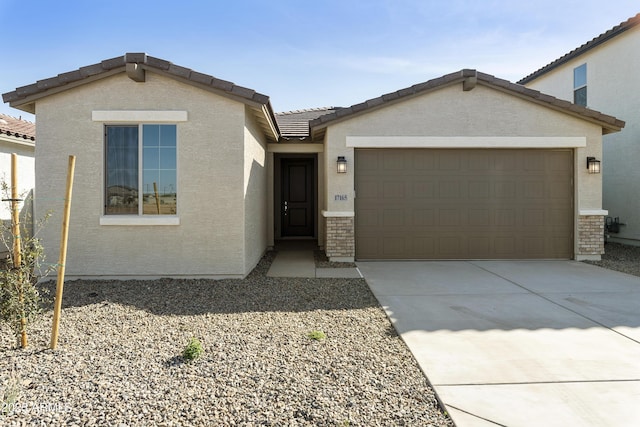 ranch-style house with a garage, driveway, a tile roof, and stucco siding