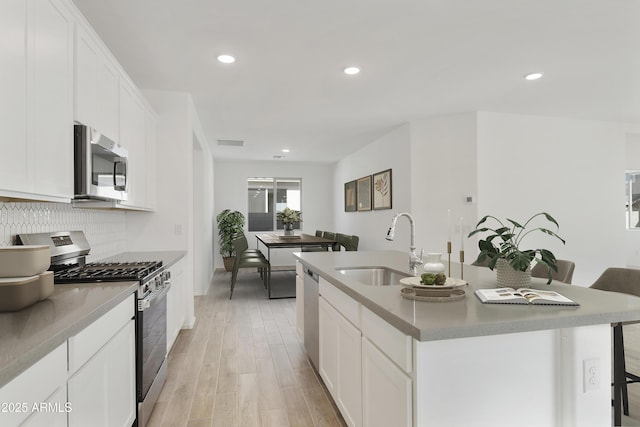 kitchen with light wood finished floors, tasteful backsplash, visible vents, appliances with stainless steel finishes, and a sink