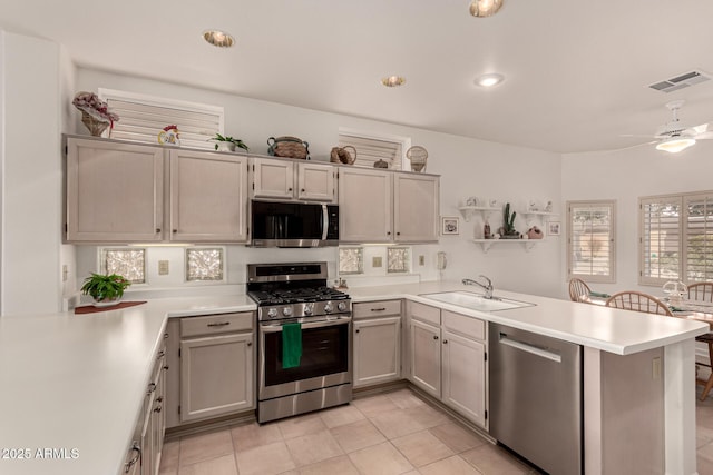 kitchen featuring stainless steel appliances, a peninsula, a sink, visible vents, and light countertops