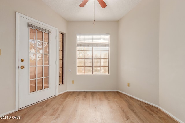 spare room with a textured ceiling, light hardwood / wood-style flooring, a wealth of natural light, and ceiling fan