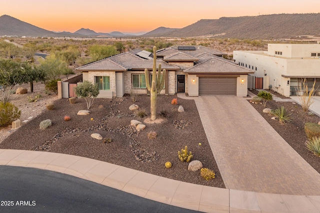 view of front facade with a garage, a mountain view, and solar panels