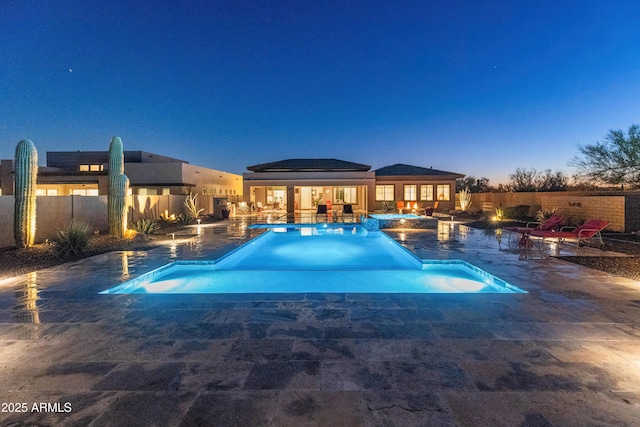 pool at dusk with a jacuzzi and a patio