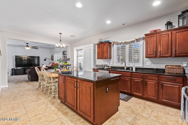 kitchen with ceiling fan with notable chandelier, a kitchen island, dark stone countertops, and hanging light fixtures