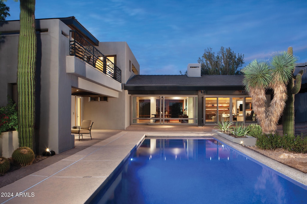 pool at dusk with a patio area