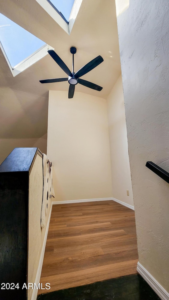 interior space with lofted ceiling with skylight, hardwood / wood-style floors, and ceiling fan