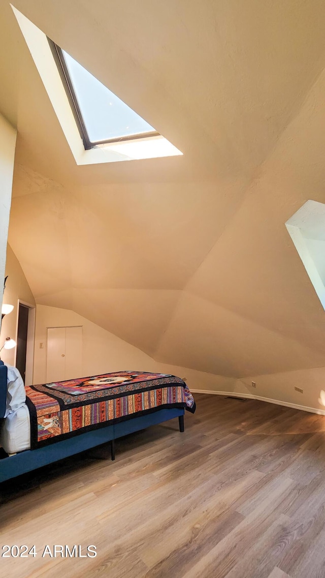 bedroom with hardwood / wood-style floors and lofted ceiling with skylight