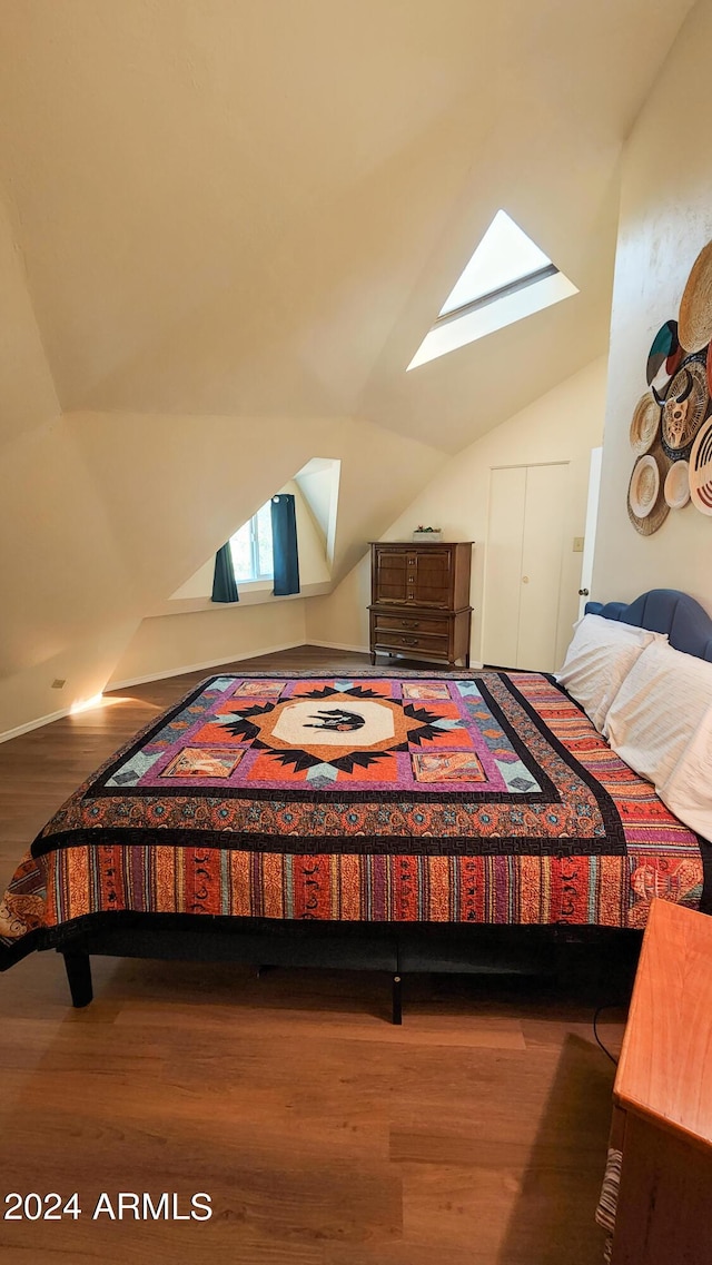 bedroom with lofted ceiling with skylight and dark hardwood / wood-style floors