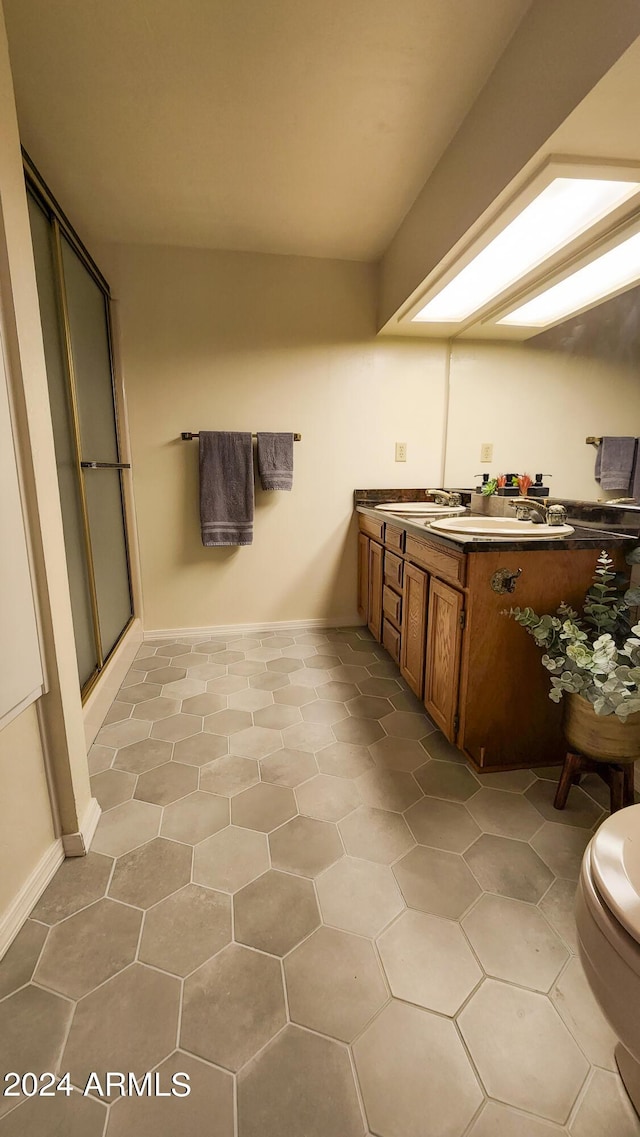 bathroom featuring tile patterned flooring, vanity, toilet, and a shower with shower door