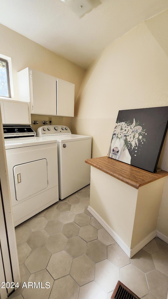 washroom with light tile patterned flooring, cabinets, and washer and dryer