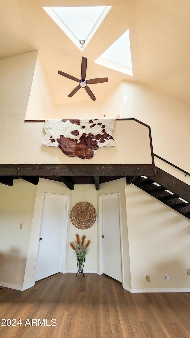 interior space with ceiling fan, hardwood / wood-style floors, beam ceiling, and a skylight