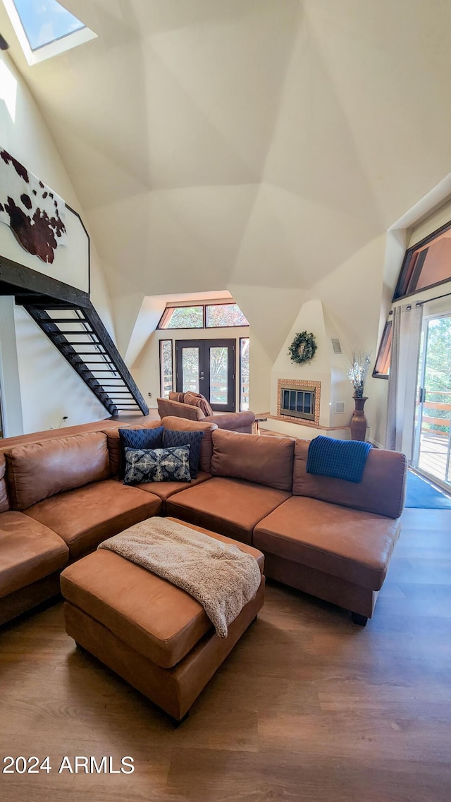 living room with a high ceiling, hardwood / wood-style floors, and a skylight