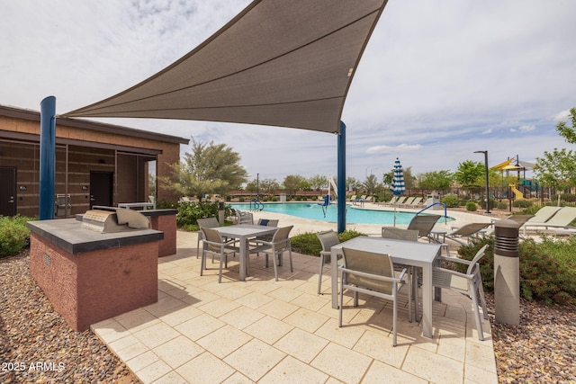 view of patio / terrace featuring a community pool, outdoor dining area, and exterior kitchen