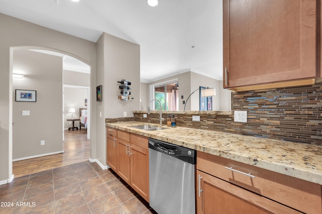 kitchen with tasteful backsplash, light stone counters, sink, and stainless steel dishwasher