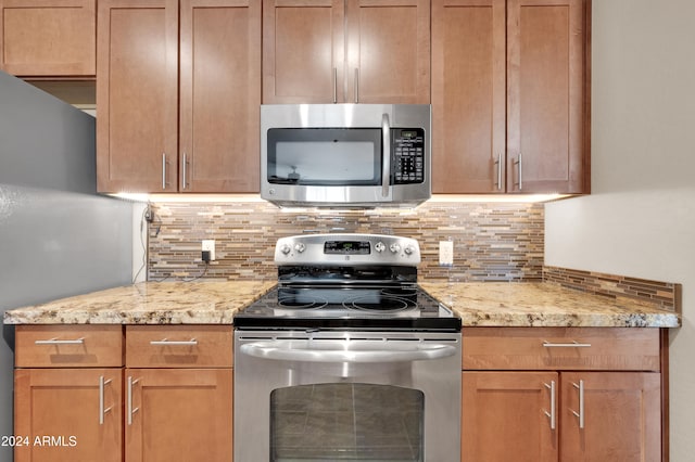 kitchen featuring decorative backsplash, light stone counters, and stainless steel appliances