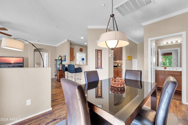 dining room with dark hardwood / wood-style floors, ceiling fan, and crown molding