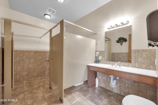 bathroom with tile patterned floors, sink, and tile walls