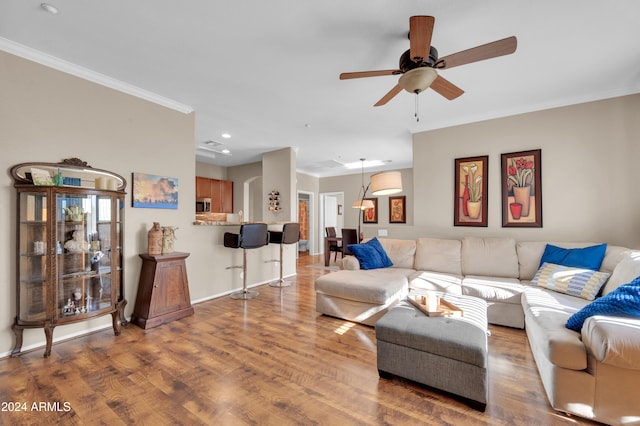 living room with wood-type flooring, ceiling fan, and crown molding