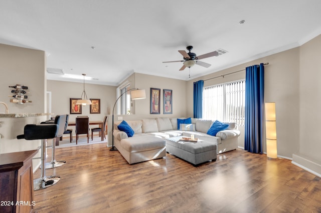 living room with crown molding, ceiling fan, and wood-type flooring