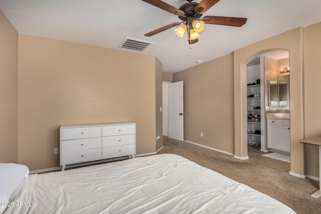 bedroom featuring light colored carpet, a spacious closet, ceiling fan, and ensuite bathroom