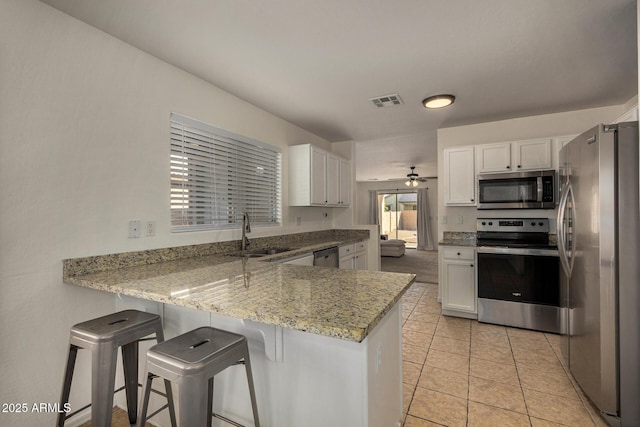 kitchen featuring sink, white cabinetry, appliances with stainless steel finishes, and kitchen peninsula