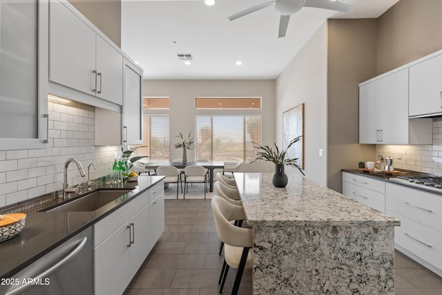 kitchen featuring sink, white cabinetry, backsplash, stainless steel appliances, and a center island