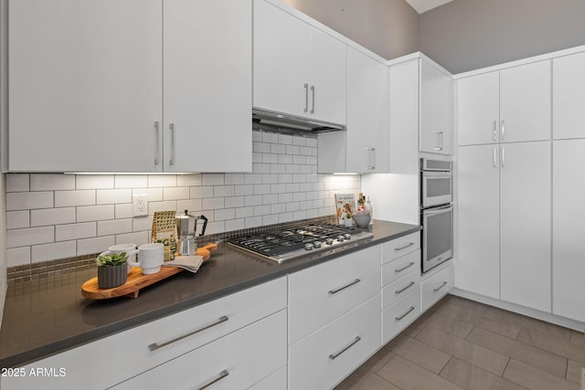 kitchen featuring tasteful backsplash, light tile patterned floors, stainless steel appliances, and white cabinets