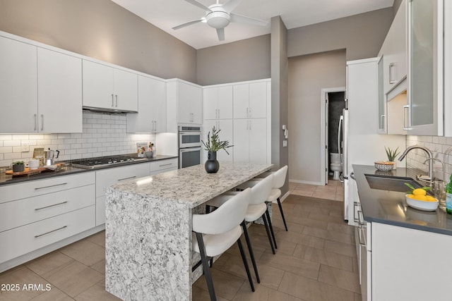 kitchen featuring sink, ceiling fan, appliances with stainless steel finishes, white cabinetry, and a kitchen breakfast bar