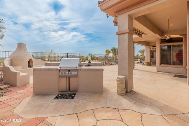 view of patio featuring ceiling fan, an outdoor kitchen, area for grilling, and exterior fireplace