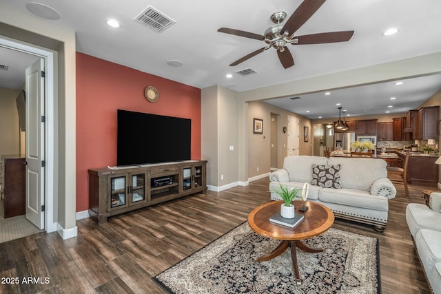 living area with visible vents, a ceiling fan, and dark wood-style flooring