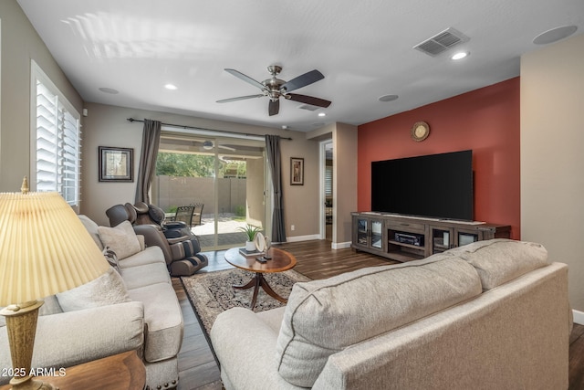 living area with visible vents, a ceiling fan, baseboards, and wood finished floors