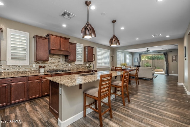 kitchen with backsplash, visible vents, dark wood-style floors, and a sink