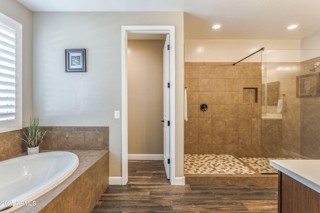 full bathroom featuring a garden tub, walk in shower, wood finished floors, and a healthy amount of sunlight
