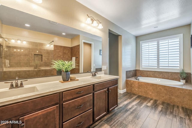 bathroom with a garden tub, a sink, wood finished floors, and double vanity