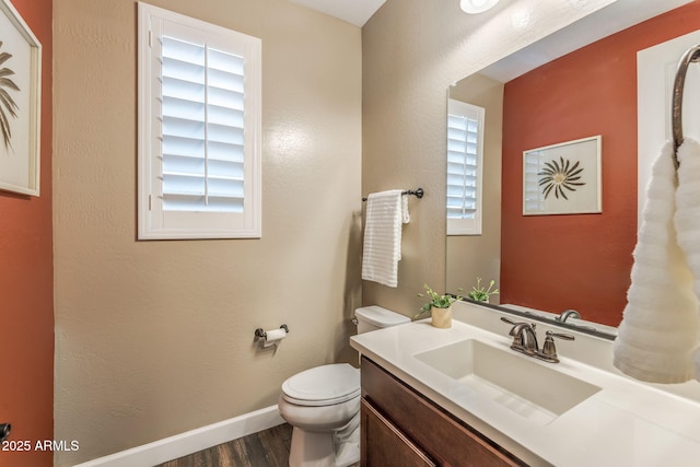 bathroom with vanity, baseboards, toilet, and wood finished floors