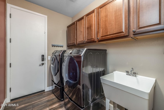 laundry area with cabinet space, a sink, separate washer and dryer, dark wood finished floors, and baseboards