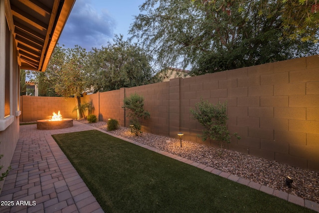 view of yard with a fenced backyard, a fire pit, and a patio area