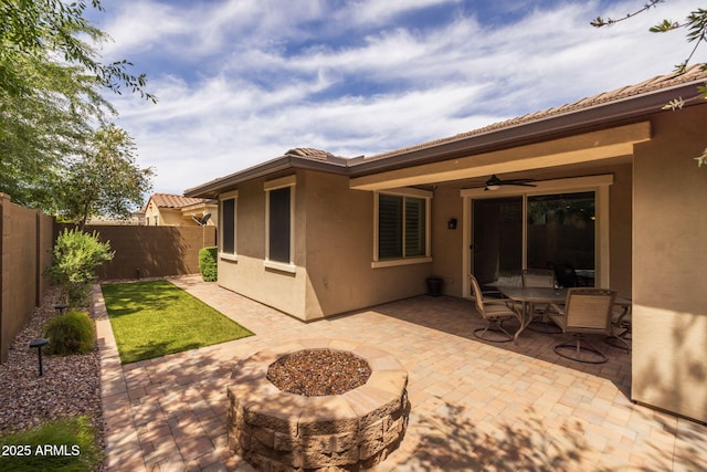 back of house with a fenced backyard, stucco siding, a ceiling fan, a patio area, and a tile roof