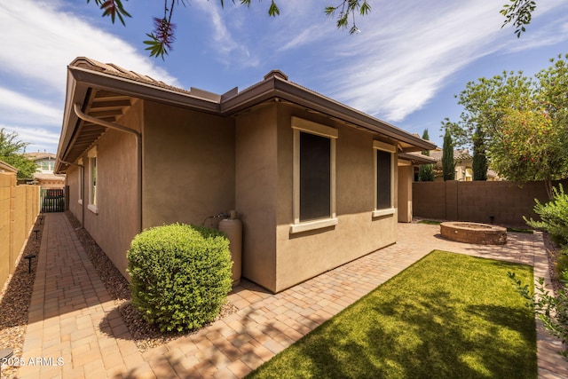 back of house with a fenced backyard, stucco siding, an outdoor fire pit, and a patio area
