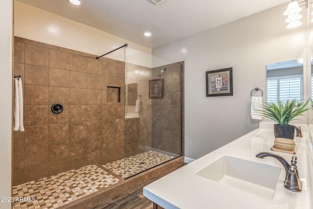 bathroom with a sink, a walk in shower, recessed lighting, and double vanity
