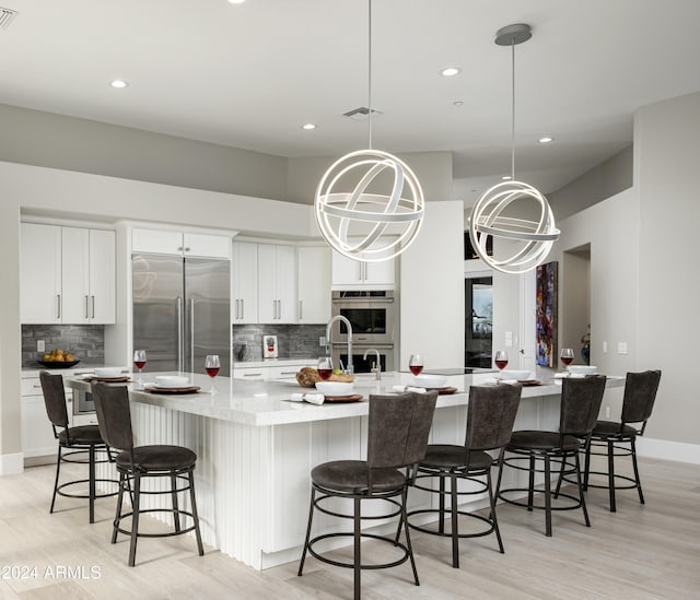 kitchen featuring a large island with sink, white cabinetry, and stainless steel appliances